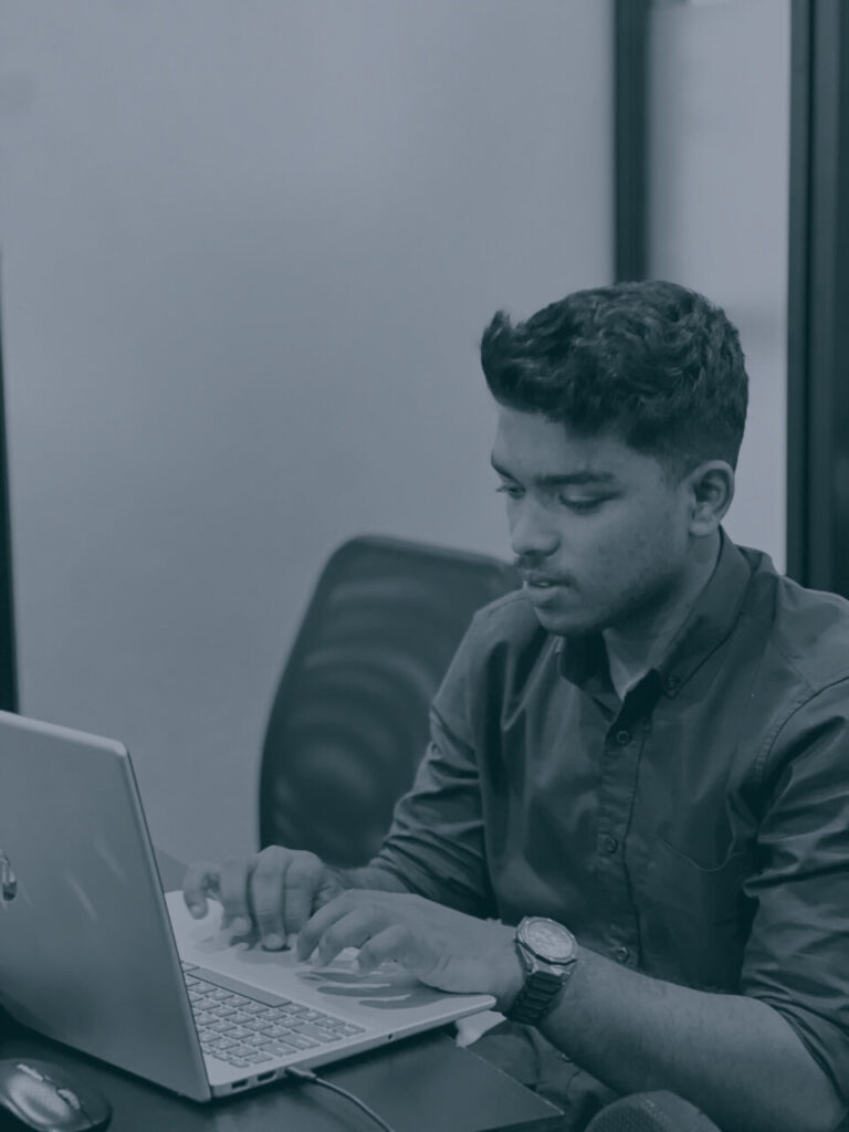 me a laptop in an office setting, wearing a button-up shirt and a wristwatch.
